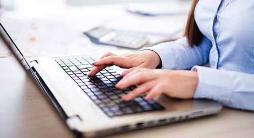 Young woman typing on a laptop computer.