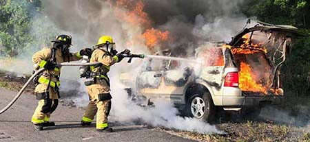 Firefighters spraying car fire
