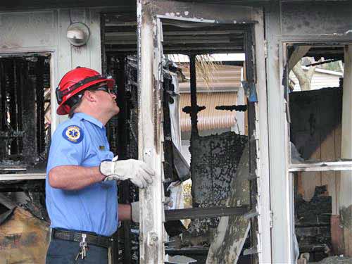 Fireman inspecting a door in a burned down house.