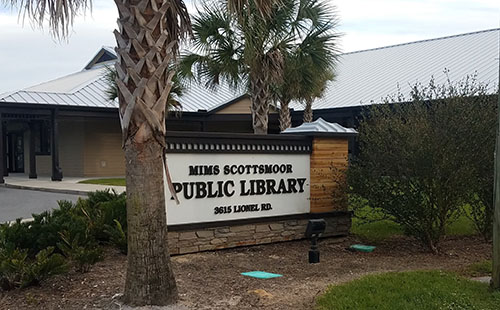 Current Mims Scottsmore Library sign, with the library building behind it.