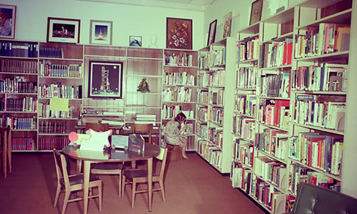 Interior of the previous Satellite Beach Public Library with a woman seated and looking at the bookshelves.