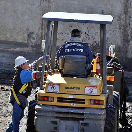 Utility Services workers using heavy machinery in sewage treatment.